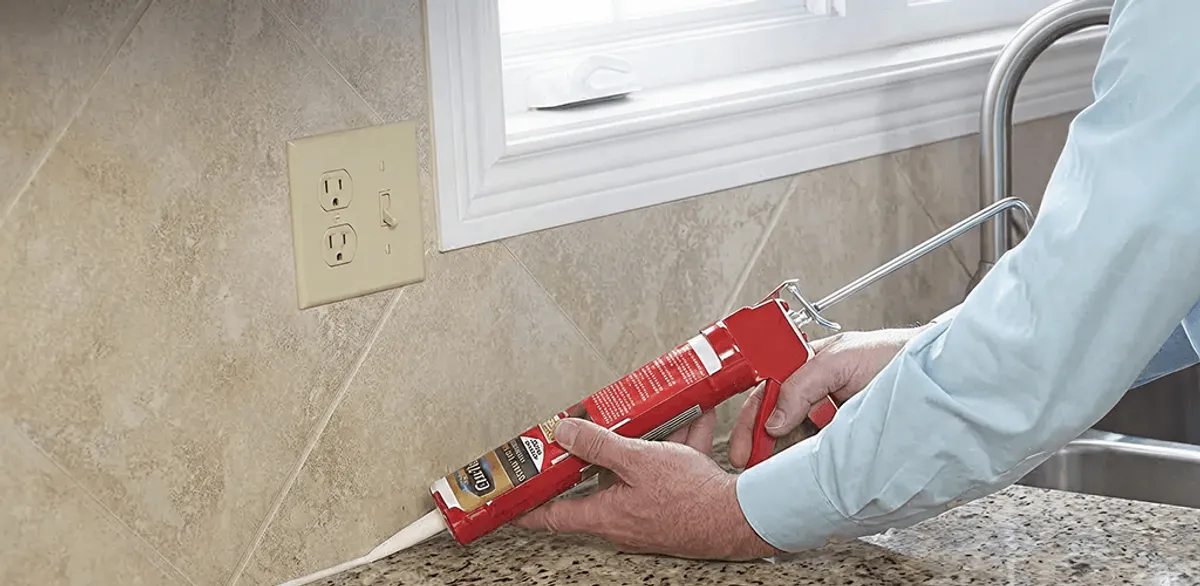 Handyman applying caulk along a kitchen backsplash and countertop seam in El Paso, TX